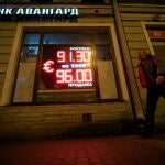 Un hombre camina frente a un panel digital que muestra el tipo de cambio del euro en una oficina de San Petersburgo, Rusia