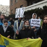 Un grupo de personas con carteles y una bandera de Ucrania participa en una nueva concentración ante la embajada rusa de Madrid