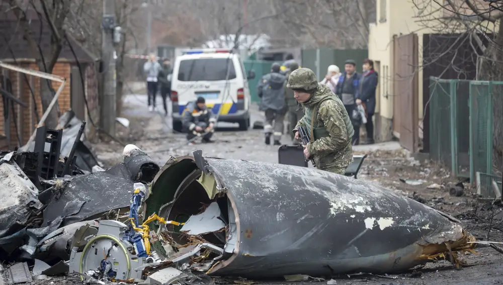A Ukrainian Army soldier inspects fragments of a downed aircraft in Kyiv, Ukraine, Friday, Feb. 25, 2022. It was unclear what aircraft crashed and what brought it down amid the Russian invasion in Ukraine. Russia is pressing its invasion of Ukraine to the outskirts of the capital after unleashing airstrikes on cities and military bases and sending in troops and tanks from three sides. (AP Photo/Vadim Zamirovsky)