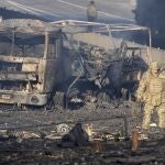 Un soldado ucraniano pasa junto a los escombros de un camión militar en llamas en una calle de Kiev