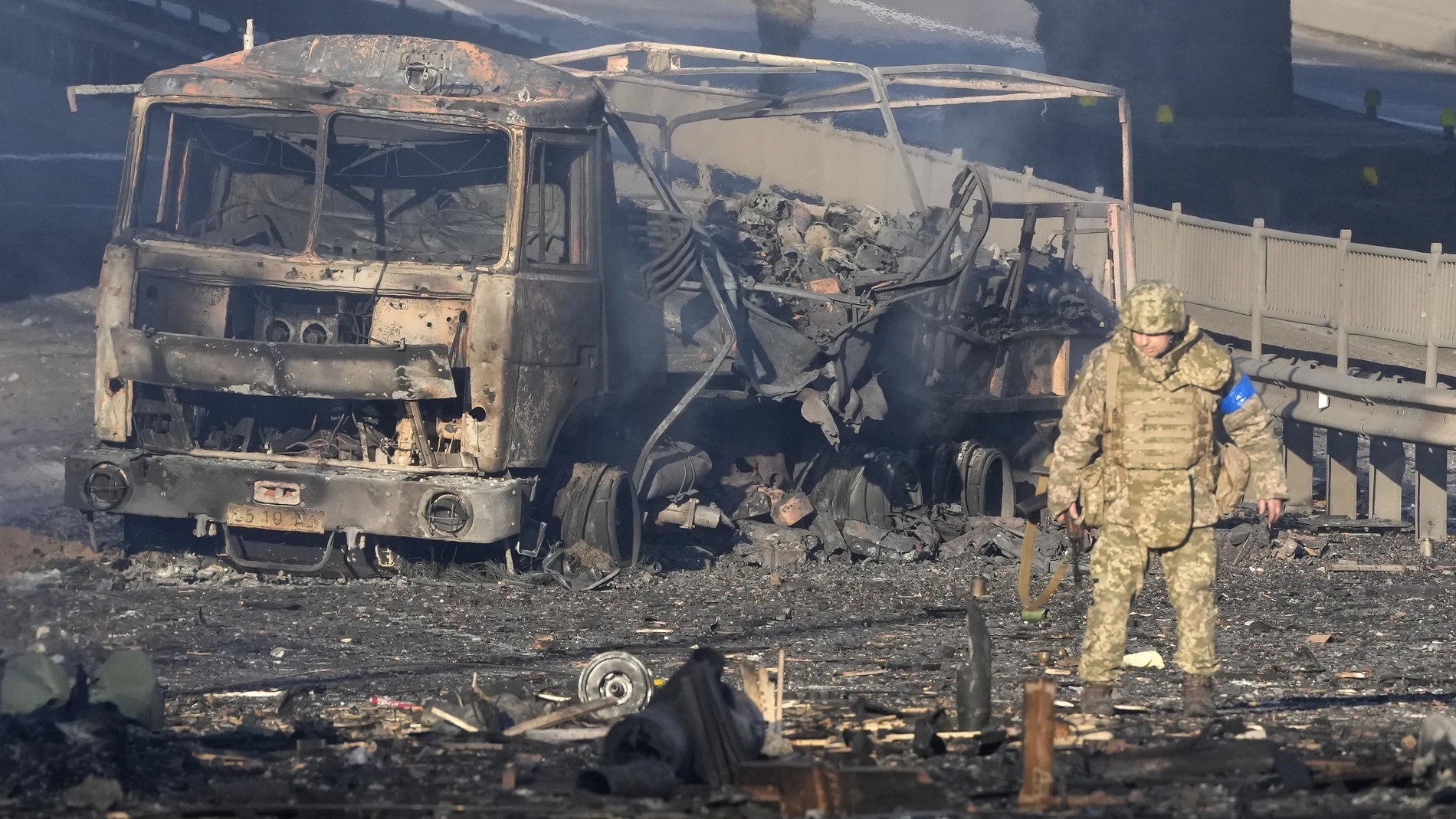Un soldado ucraniano pasa junto a los escombros de un camión militar en llamas en una calle de Kiev