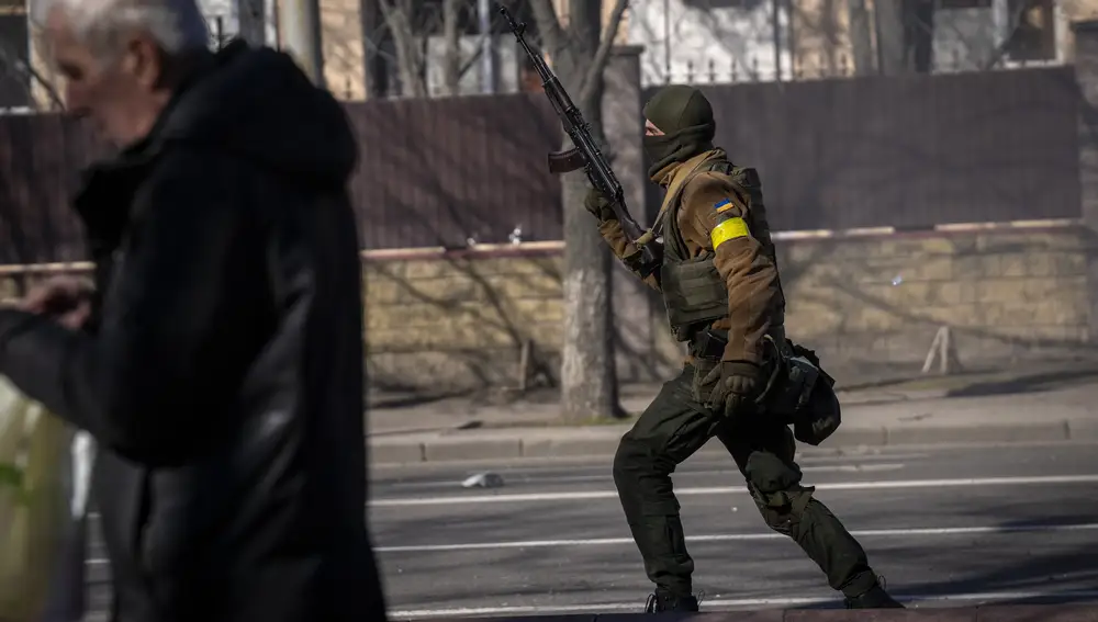Un soldado ucraniano corre sosteniendo su arma frente a una instalación militar en Kiev