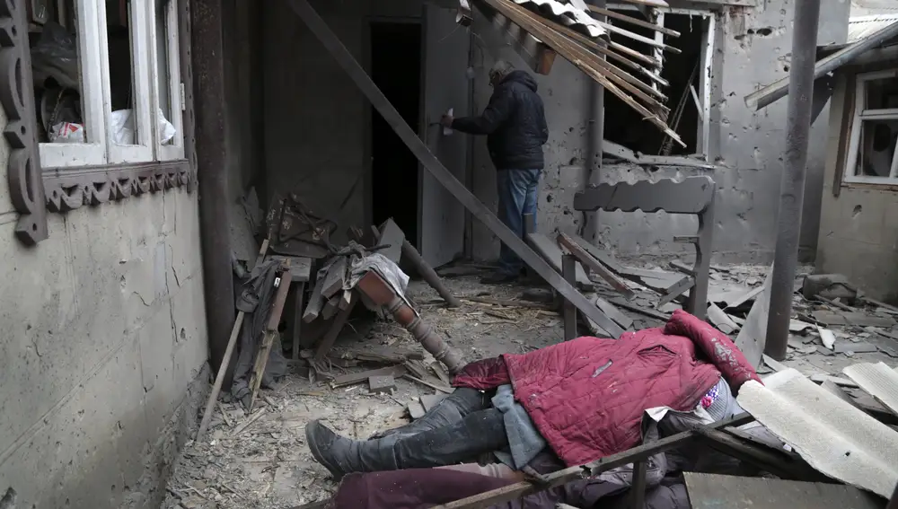 El cuerpo de una mujer, muerta durante un bombardeo, yace bajo los escombros de una casa dañada en Donetsk, en el territorio controlado por militantes prorrusos, en el este de Ucrania