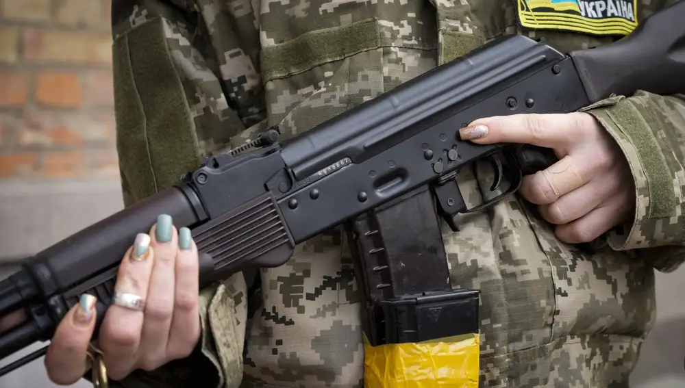 Una mujer armada de defensa civil sostiene un rifle de asalto Kalashnikov mientras patrulla una calle vacía debido al toque de queda en Kiev