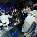Varios visitantes esperan a ser servidos por un robot barman en el stand de Telefónica durante la jornada inaugural de Mobile World Congress de Barcelona
