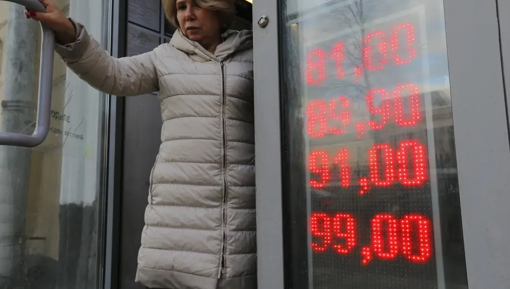 En esta foto del 24 de febrero de 2022, una mujer sale de una oficina de cambio con una pantalla que muestra las tasas de cambio del dólar estadounidense y el euro a rublos rusos en Moscú, Rusia | Fuente: AP Photo/Alexander Zemlianichenko Jr