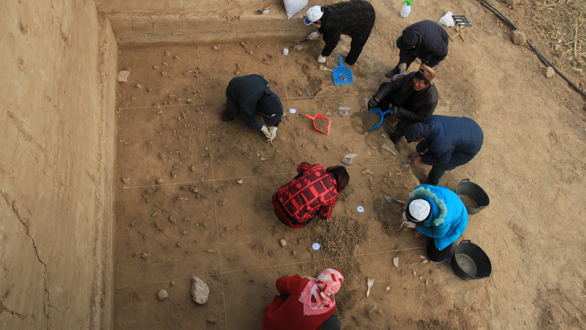 Arqueólogos excavando la superficie bien conservada del yacimiento de Xiamabei, en el norte de China, mostrando herramientas de piedra, fósiles, ocre y pigmentos rojos.