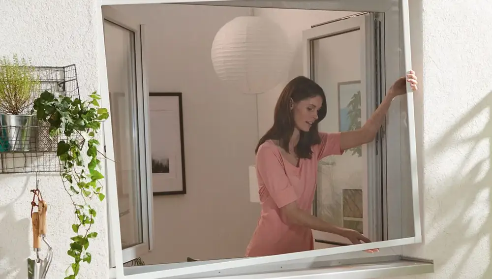 Mujer quitando una mosquitera de aluminio de la ventana