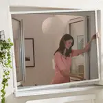 Mujer quitando una mosquitera de aluminio de la ventana