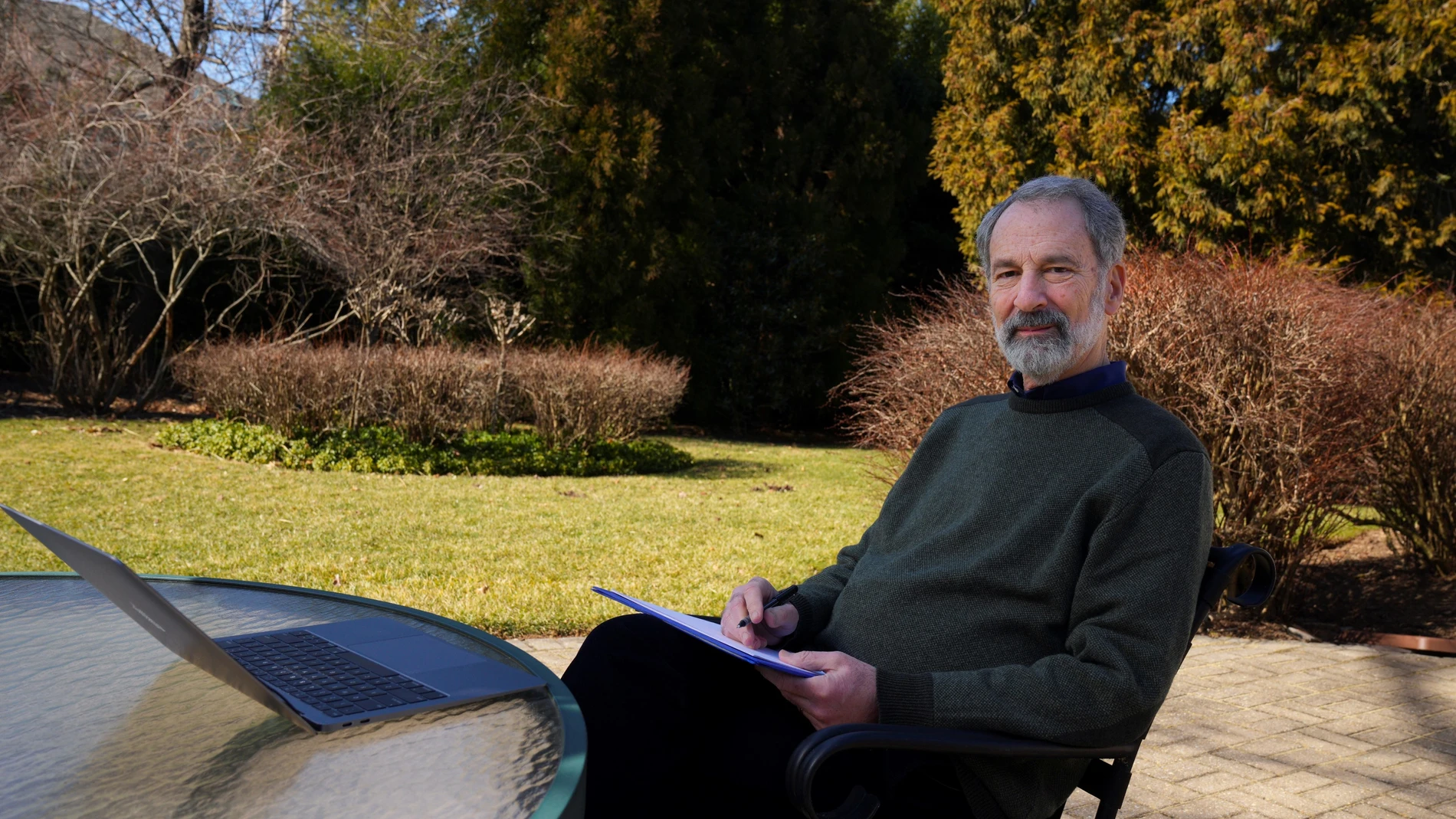 Charles Fefferman en el jardín de su casa de Princeton, sentado con unos papeles y su ordenador