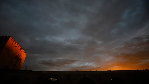 Varias personas caminan por el puente Romano de Córdoba y junto a la torre de la Calahorra en un jornada de cielos muy nubosos. EFE/Salas
