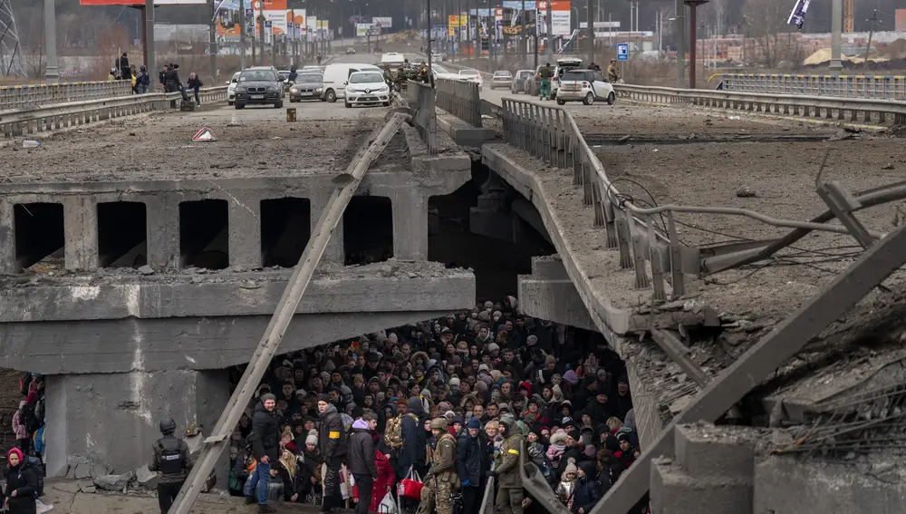 Decenas de ciudadanos ucranianos, bajo el puente destruido de Irpin, son ayudados por el ejército de su país para cruzar el río