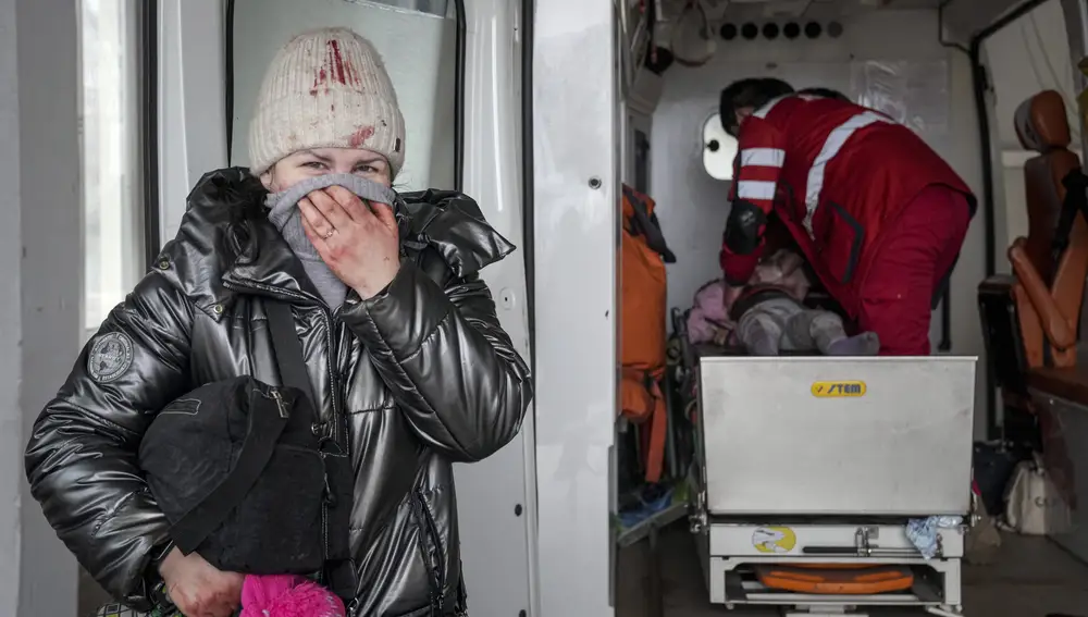 Una mujer lleva al hospital a una niña herida en Mariupol