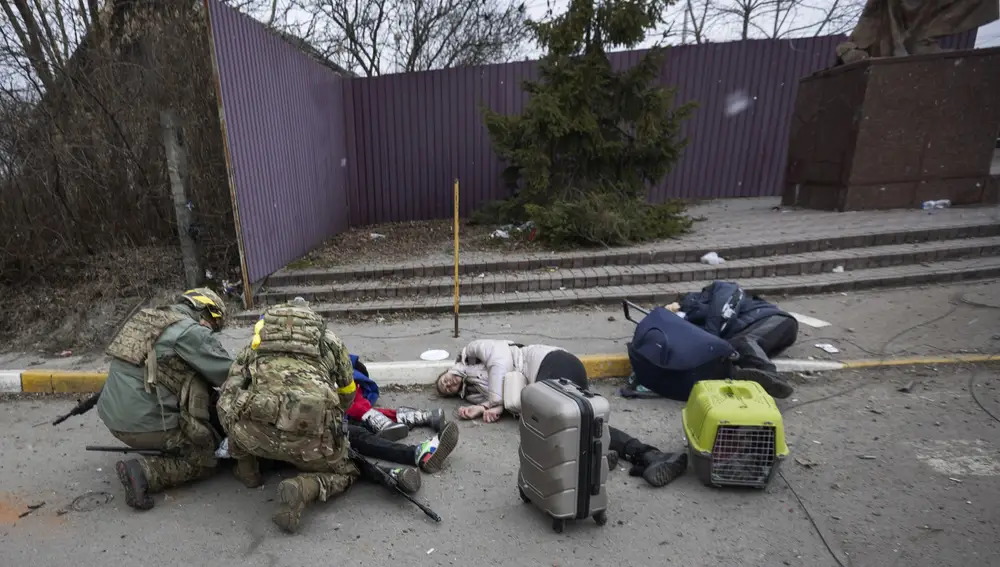 Militares ucranianos junto a los cuerpos de Tatiana y sus dos hijos asesinados cuando trataban de salir de la ciudad de Irpin, donde vivían