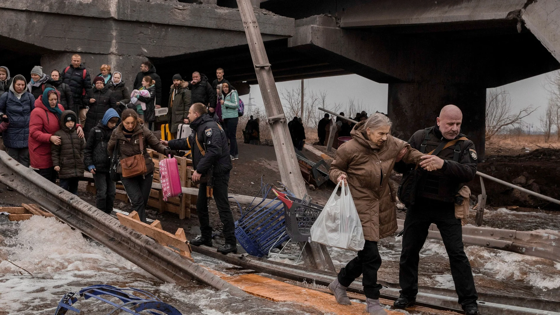 Ciudadanos ucranianos cruzan un puente destruido mientras huyen de su ciudad en Irpin, cerca de Kiev