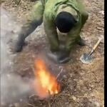 Un soldado ucraniano aviva el fuego usando una bolsa de plástico para introducir aire en el segundo hoyo.
