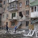 Varias personas junto a un edificio de apartamentos alcanzado por los bombardeos en Mariúpol, Ucrania