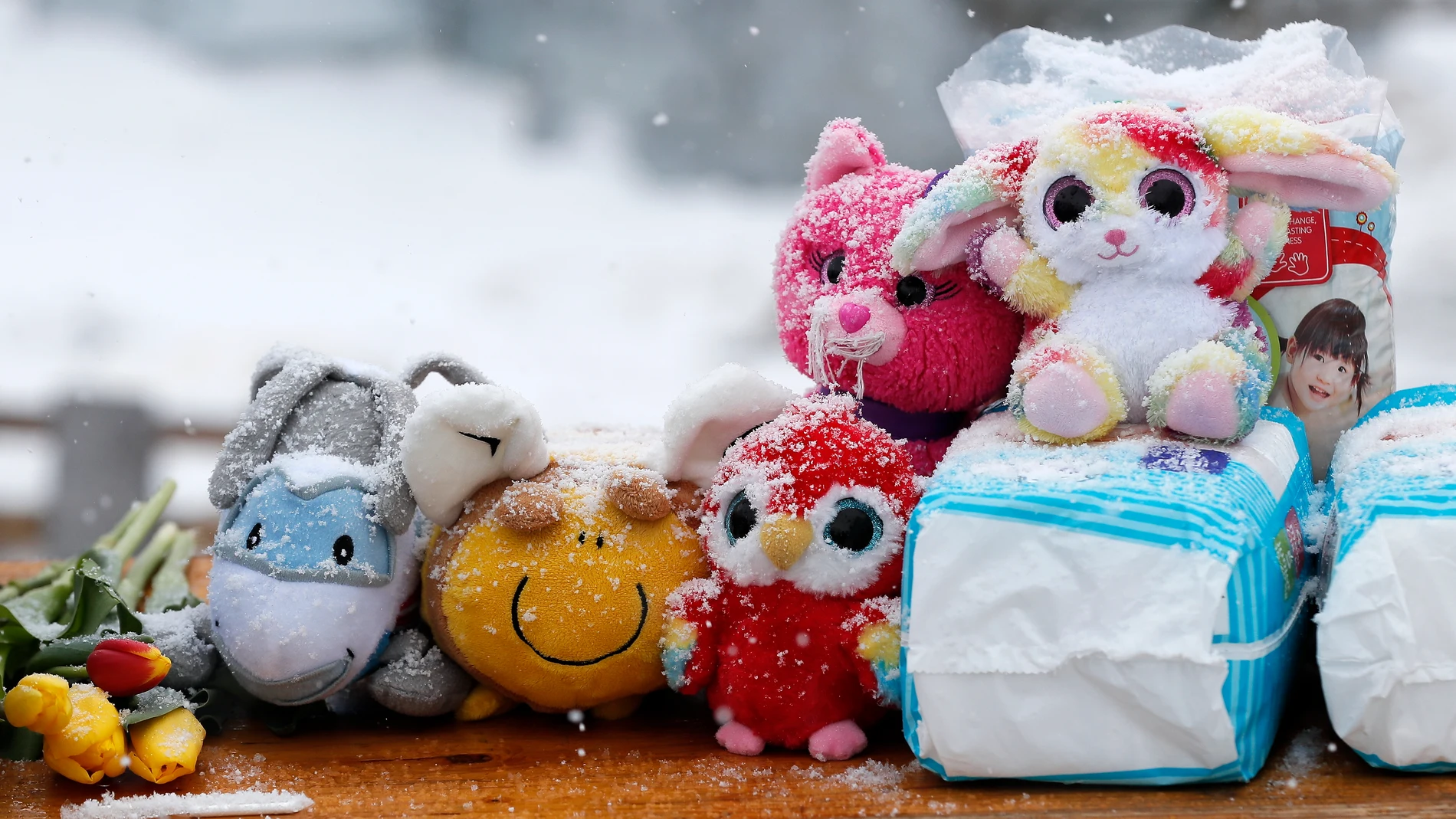 La nieve cubre los juguetes para niños y los productos de cuidado para bebés en una mesa que muestra productos de ayuda para los niños ucranianos, en el paso fronterizo de Siret (Rumanía)