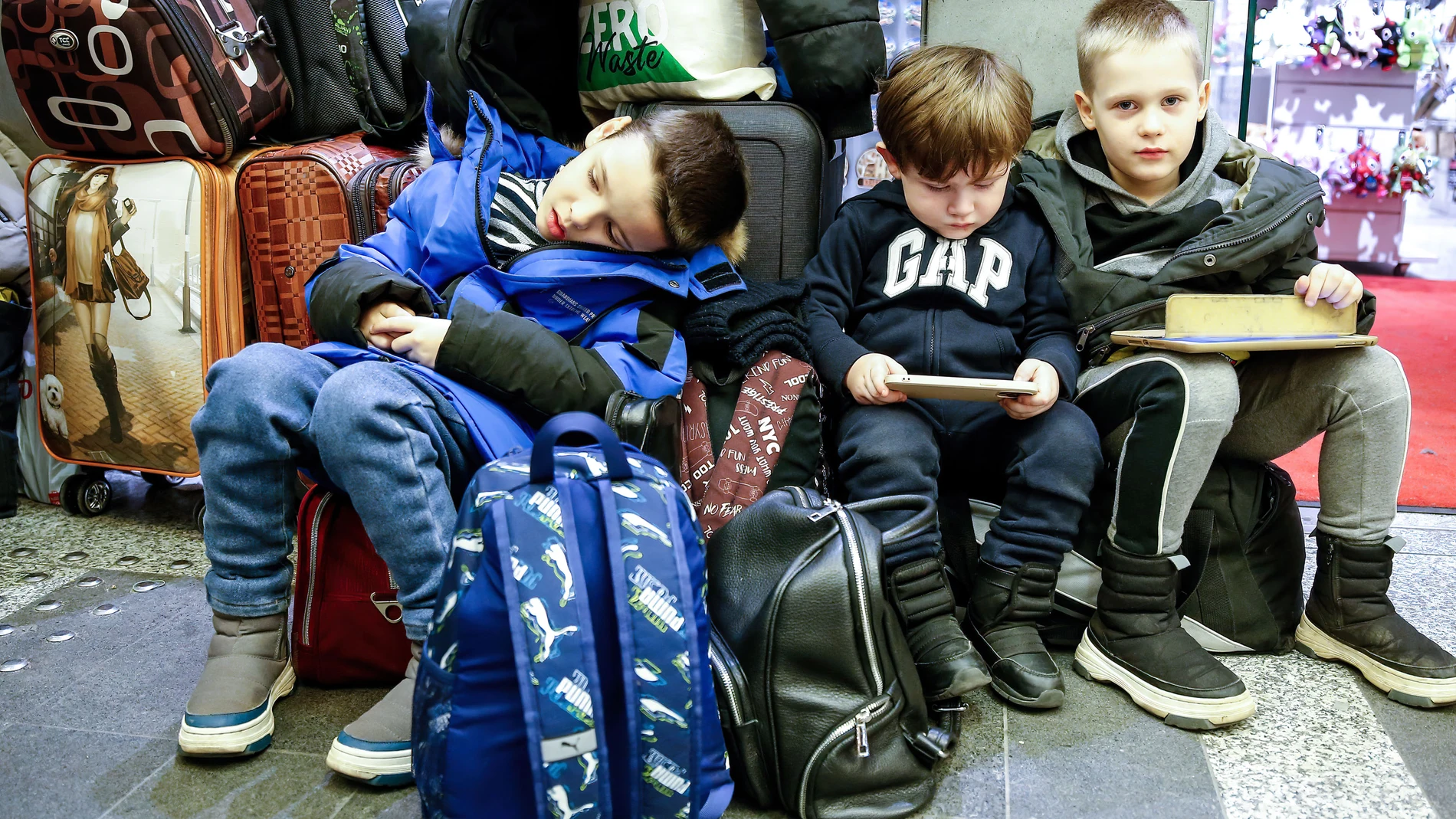 Niños ucranianos refugiados descansan sobre su equipaje tras llegar a la estación principal de tren de Cracovia