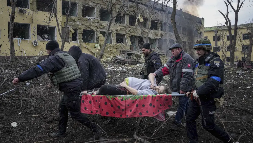 FILE - Ukrainian emergency employees and volunteers carry an injured pregnant woman from a maternity hospital that was damaged by shelling in Mariupol, Ukraine, March 9, 2022. The woman and her baby died after Russia bombed the maternity hospital where she was meant to give birth. (AP Photo/Evgeniy Maloletka, File)