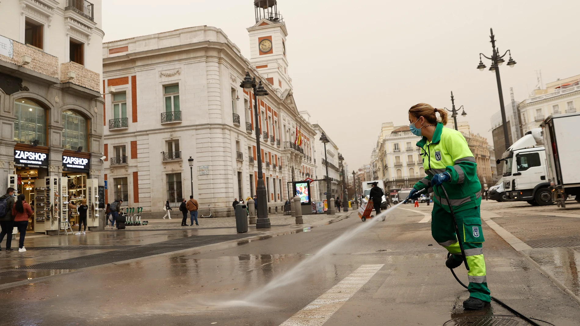 Trabajadores de la limpieza retiran en la Puerta del Sol el polvo en suspensión que proviene del Sáhara que tras la lluvia acaecida en Madrid este martes ha teñido la ciudad de un color naranja. EFE/ Chema Moya