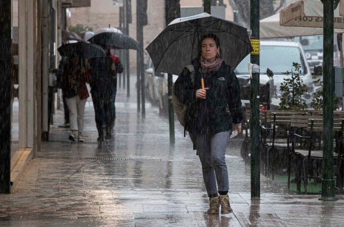 Varias personas se resguardan de la lluvia en la Gran Vía de Murcia