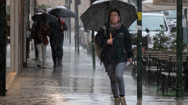 Varias personas se resguardan de la lluvia en la Gran Vía de Murcia