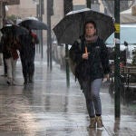 Varias personas se resguardan de la lluvia en la Gran Vía de Murcia