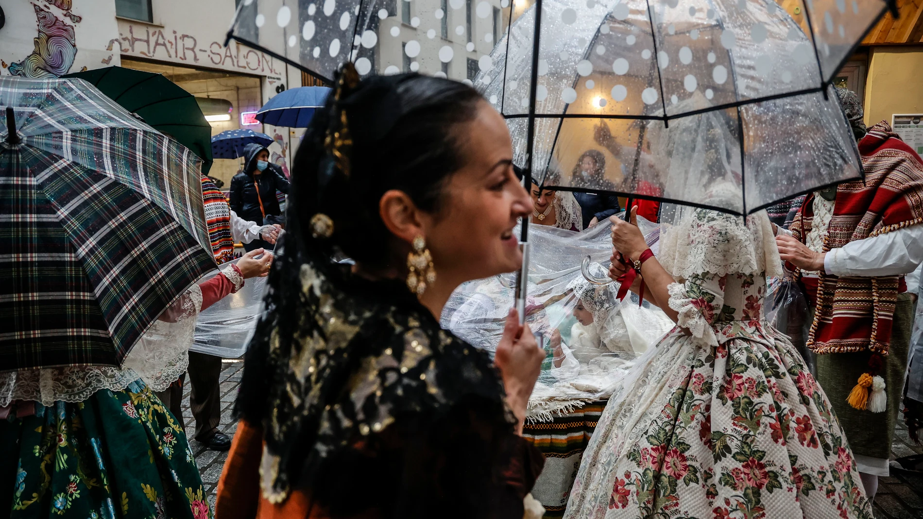 Una fallera se cubre con un paraguas en la ofrenda floral a la Virgen de los Desamparados, ayer