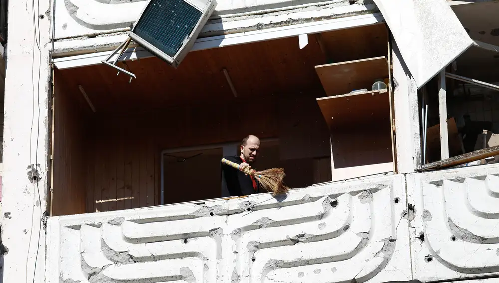 Un hombre limpiando el balcón de un apartamento después de un ataque con cohetes que destruyó un edificio residencial en Kiev