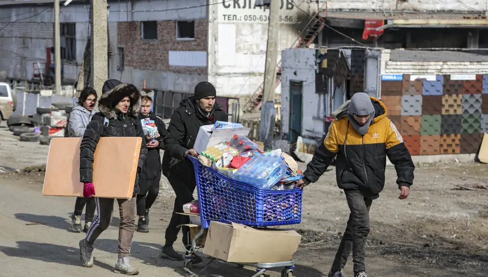 Varias personas cargan agua desde el almacén de alimentos, en el territorio que está bajo el control del Gobierno de la República Popular de Donetsk, en las afueras de Mariupol