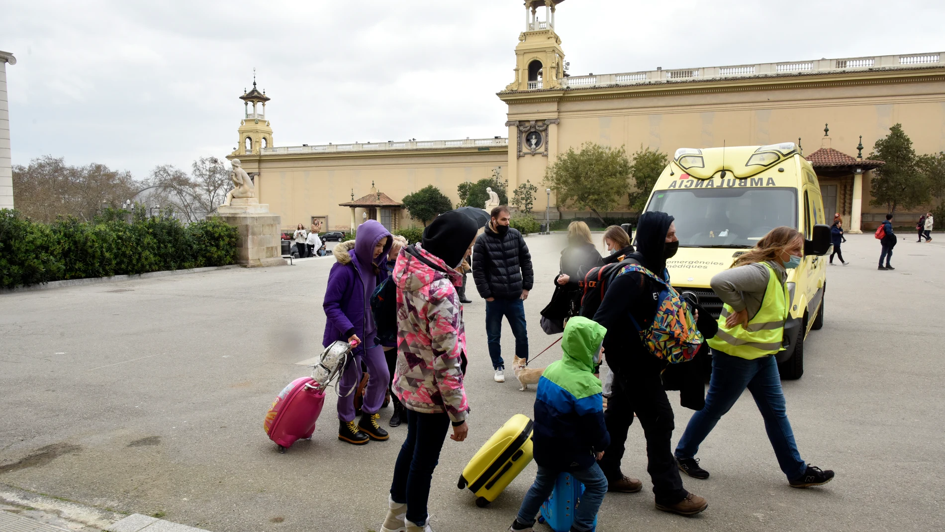 Varios refugiados y una traductora, junto a una ambulancia, en la entrada del palacio de Victoria Eugenia, el palacio 7 de Fira de Barcelona, convertido en un centro de recepción y atención de refugiados de Ucrania, a 18 de marzo de 2022, en Barcelona.