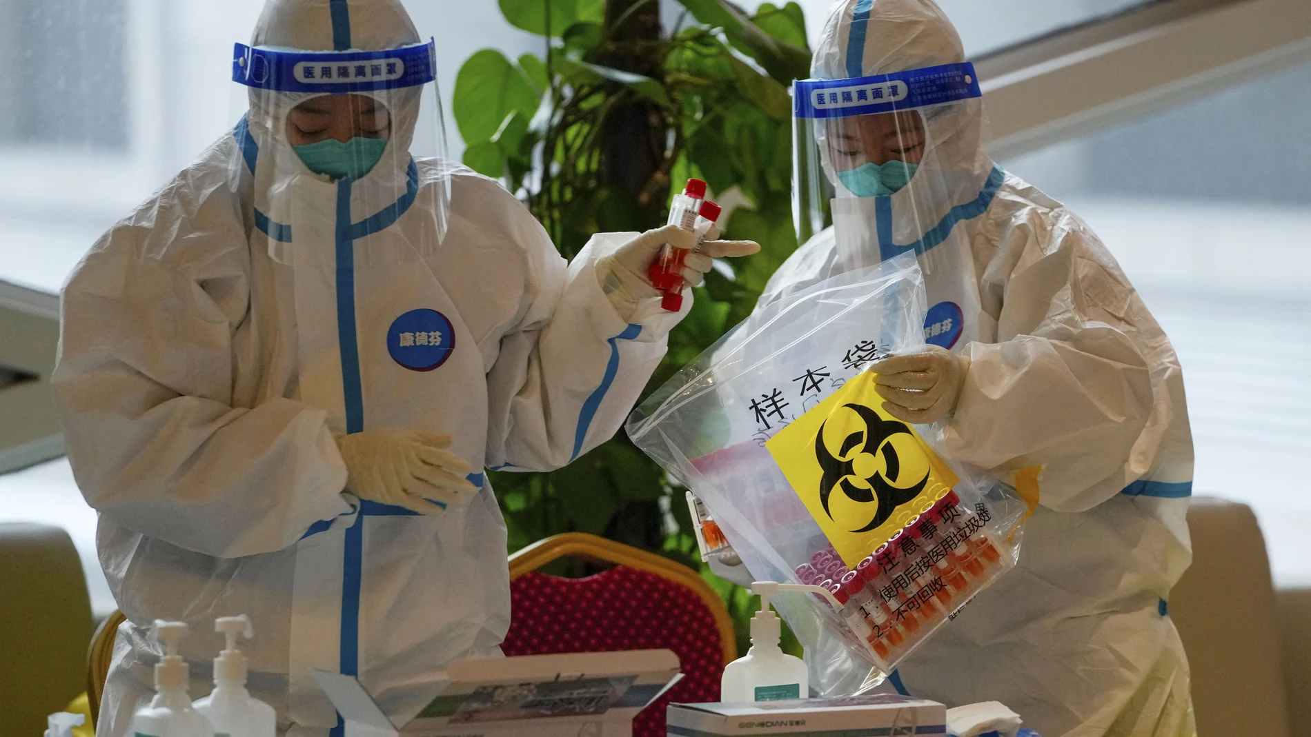 Sanitarios con trajes protectores colocan muestras de pruebas Covid-19 en una bolsa en Beijing