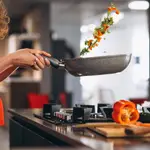 Mujer cocinando verduras en una sartén