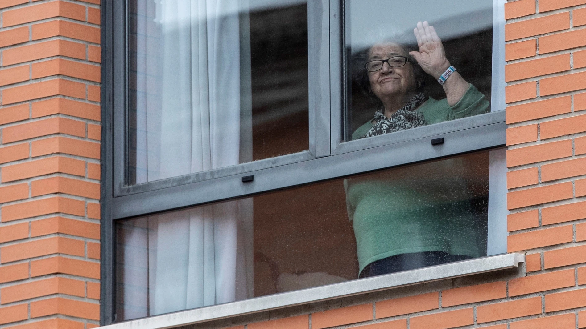Una mujer confinada saluda desde la ventana en la Región de Murcia