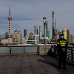 Un policía chino monta guardia en el Bound con el principal distrito financiero de Pudong al fondo, en Shanghái