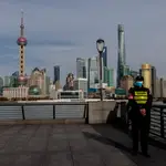 Un policía chino monta guardia en el Bound con el principal distrito financiero de Pudong al fondo, en Shanghái