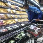 Un repartidor selecciona artículos de estantes parcialmente vacíos en Shanghái, China, el miércoles 30 de marzo de 2022.