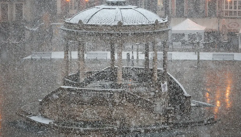 Dos personas cruzan la Plaza del Castillo de Pamplona bajo una intensa nevada este viernes.