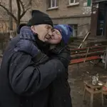 Una mujer besa a un hombre mientras cocina en una fogata fuera de un edificio de apartamentos sin electricidad en Bucha, Ucrania