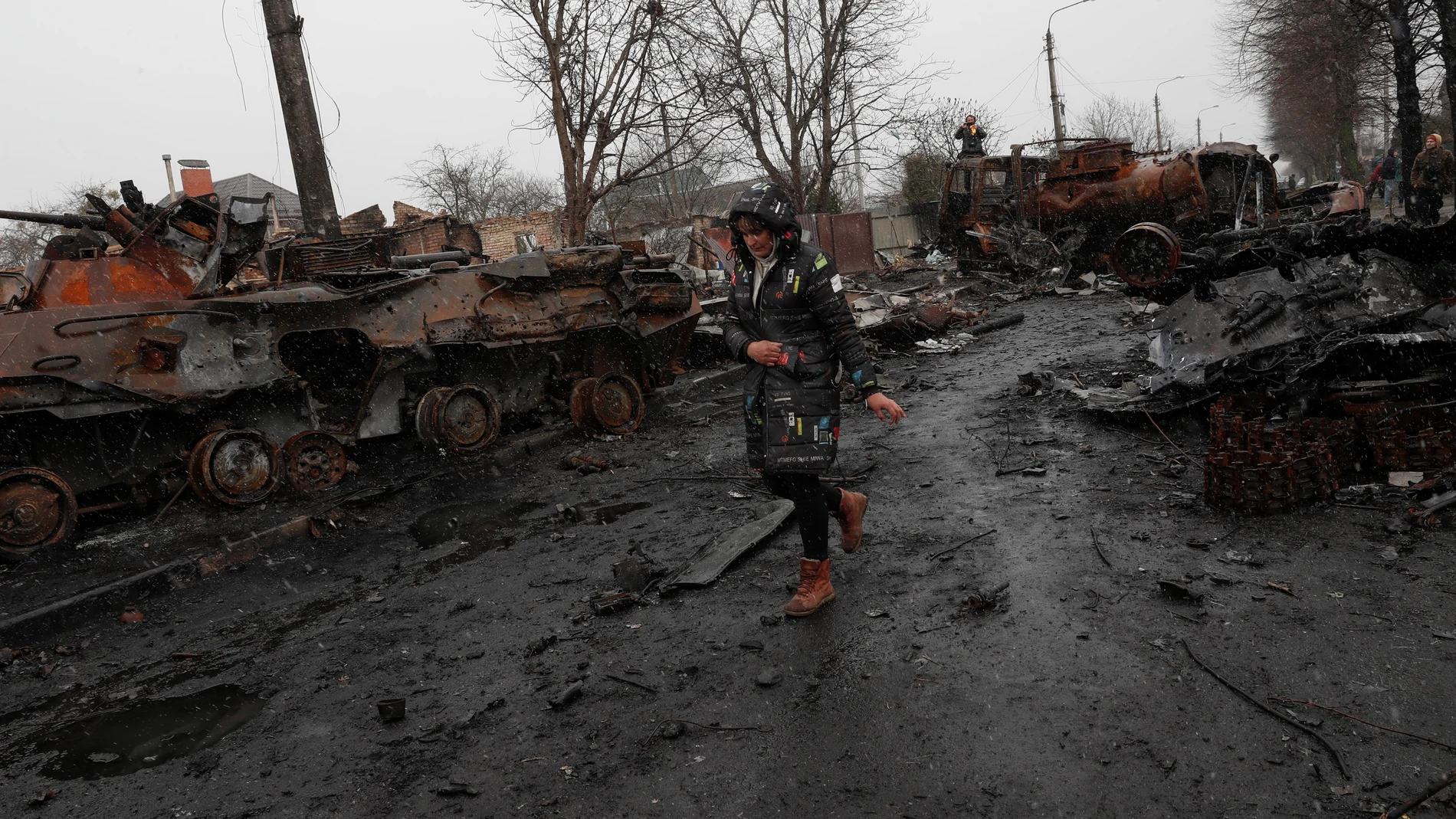 Una mujer pasa por la calle devastada de Bucha en la que se observa la destrucción de los carros de combate rusos