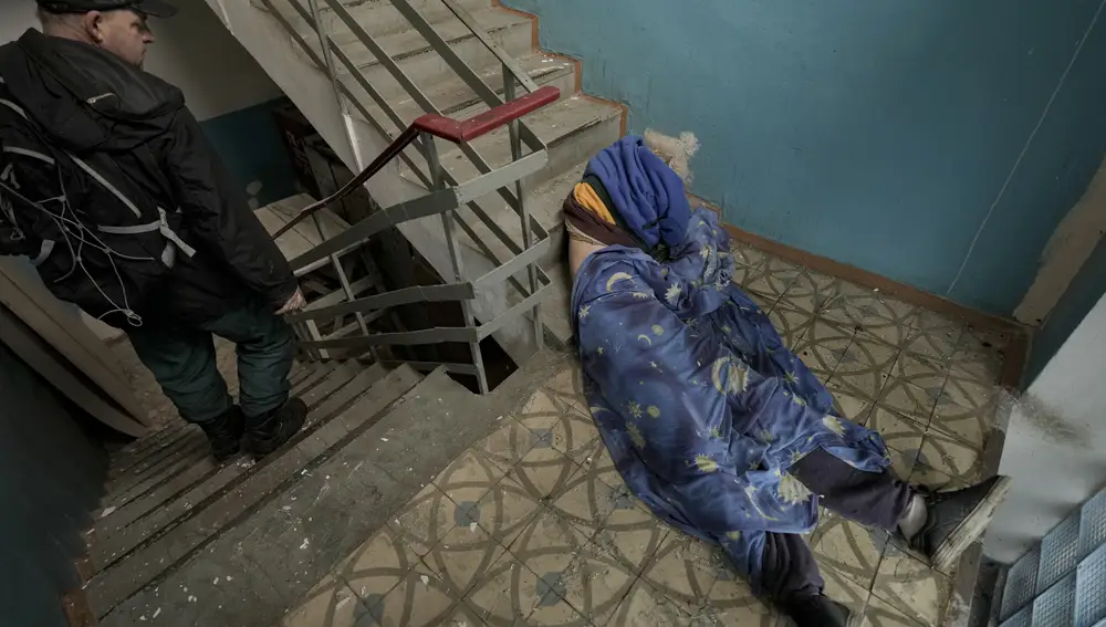 Un hombre yace en las escaleras de un edificio en Bucha