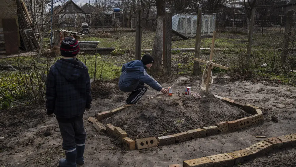 Vladimir, de 10 años, deposita un zumo de naranja en la tumba de su madre