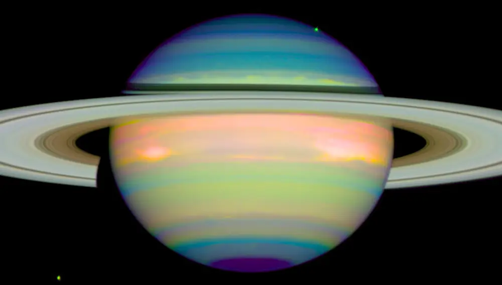 Esta imagen en falso color de Saturno captura la luz infrarroja que se refleja en el planeta. La imagen, tomada el 4 de enero de 1998, también captura dos de las lunas de Saturno, Dione en la esquina inferior izquierda y Tethys en la esquina superior derecha.
