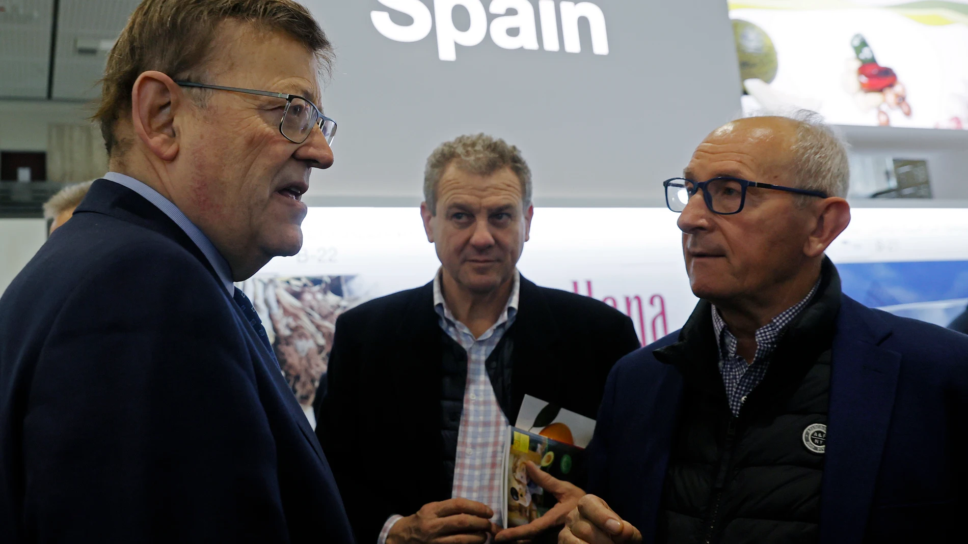 El president de la Generalitat, Ximo Puig (i), conversa con el presidente de AVA-Asaja, Cristóbal Aguado, en el stand de España durante su visita a las empresas de la Comunitat Valenciana que participan en el certamen alemán, Fruitlogistic