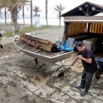 Dos hosteleros recogen los desperfectos causados por el temporal en su chiringuito en la playa de Huelín, en Málaga.