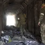 Militares de la milicia de la autoproclamada República Popular de Donetsk observan los cuerpos de los soldados ucranianos colocados en bolsas de plástico en un túnel