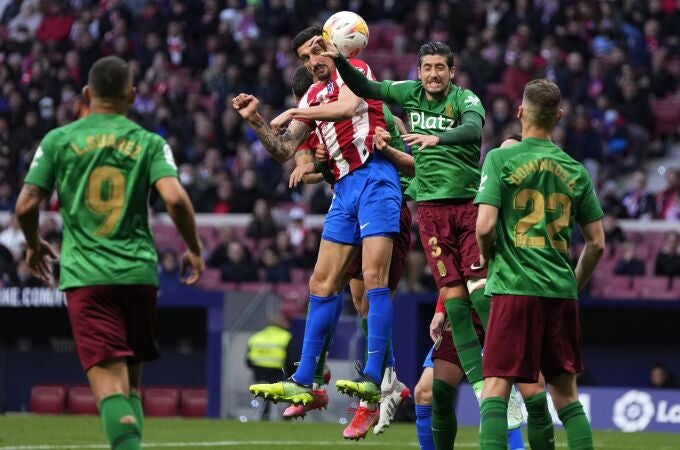 Sergio Escudero y Savic saltan a por un balón en el Atlético - Granada