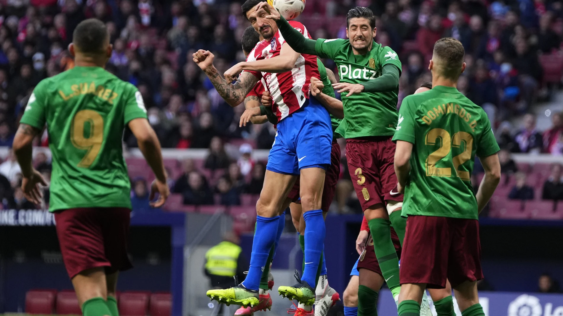 Sergio Escudero y Savic saltan a por un balón en el Atlético - Granada