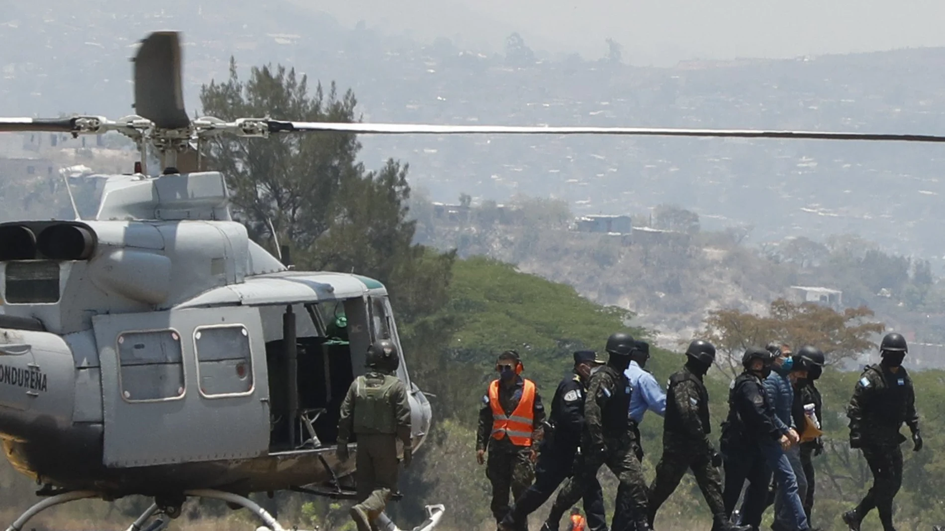 Former Honduran President Juan Orlando Hernandez, right, is escorted in handcuffs by soldiers and police as they arrive to an Air Force base in Tegucigalpa, Honduras, Thursday, April 21, 2022. Honduras’ Supreme Court approved the extradition of Hernández to the United States to face drug trafficking and weapons charges. (AP Photo/Elmer Martinez)